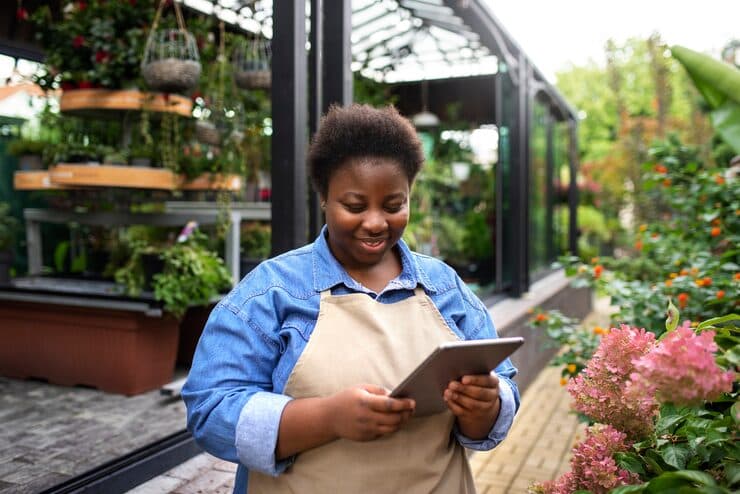 A shop owner using a tablet in a garden centre